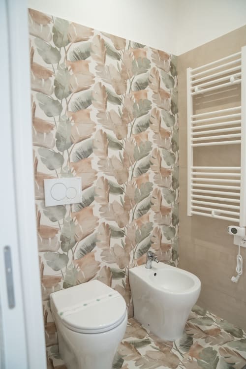 Modern bathroom at Ruah Pompei with botanical leaf wallpaper, white toilet and bidet, heated towel rack, Pompei