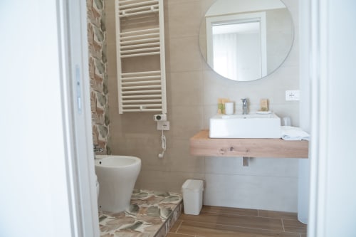 Modern bathroom in Ruah Pompei B&B, Pompei with white sink, round mirror, heated towel rack, and tiled shower area