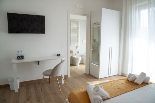 Modern triple room at Ruah Pompei with flat-screen TV, work desk, and ensuite bathroom in Pompeii, Italy