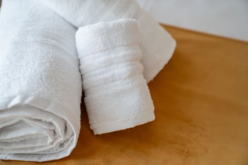 Rolled white towels on wooden surface at Ruah Pompei bed and breakfast in Pompeii