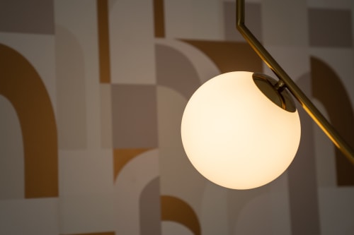Spherical pendant light fixture in Ruah Pompei room with warm glow and decorative wall shadows