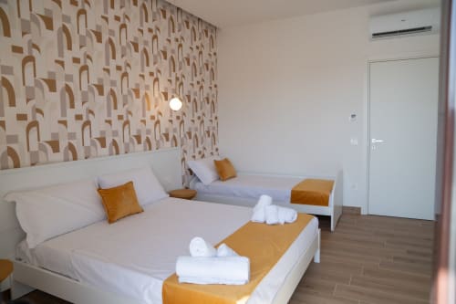 Triple room with two beds at Ruah Pompei, Pompeii. Modern decor with gold accents, air conditioning, and flat-screen TV.