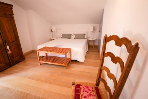 Spacious double bedroom at Casa Rural La Perla with wooden furnishings, white bedding, and wooden flooring in Hiendelaencina
