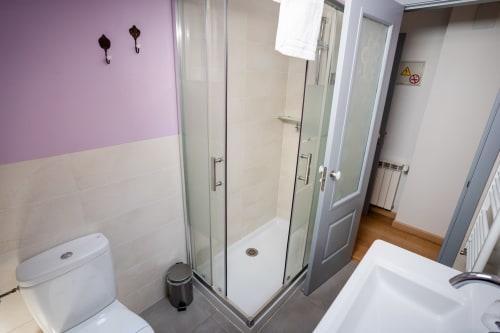 Baño moderno en Casa Rural La Perla con ducha, inodoro, bañera y toallero calefactor