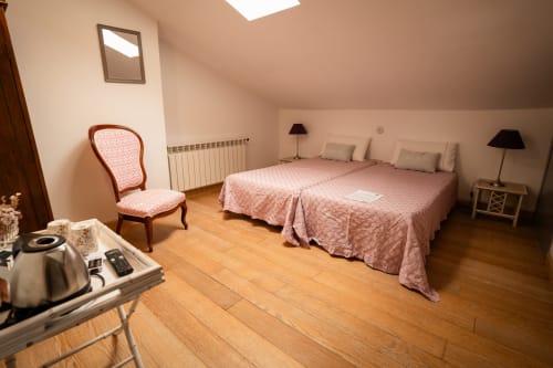 Twin bedroom at Casa Rural La Perla with pink bedding, wooden floors, and period furniture in Hiendelaencina