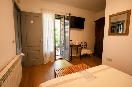 Bright double bedroom at Casa Rural La Perla with terrace access, wooden floors, TV, and garden views
