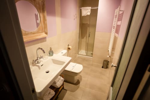 Modern bathroom at Casa Rural La Perla with sink, toilet, shower, and pink and cream tiled walls in Hiendelaencina