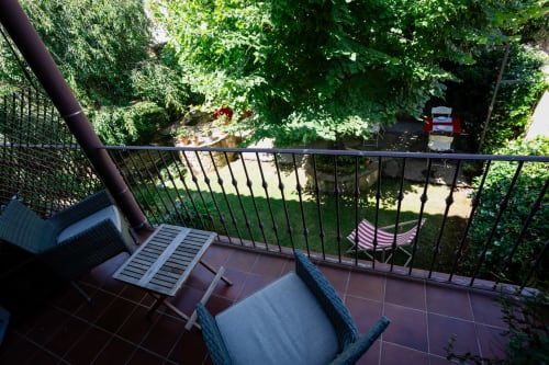 Terrace with wicker chairs overlooking lush green gardens at Casa Rural La Perla, Hiendelaencina