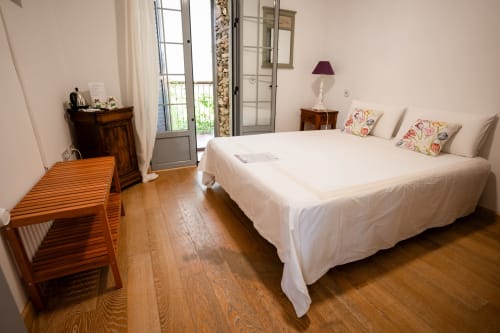 Bright double bedroom with white bedding, wooden furniture, and balcony access at Casa Rural La Perla in Hiendelaencina