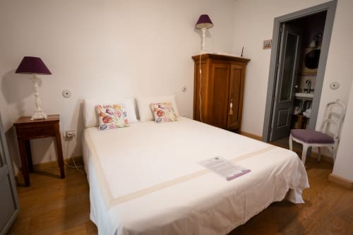 Chambre double élégante à Casa Rural La Perla avec literie blanche, oreillers fleuris, mobilier en bois et salle de bain attenante