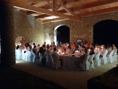 Wedding reception dinner in historic stone venue at L'Amiradou, Félines-sur-Rimandoule, with candlelit tables and wooden