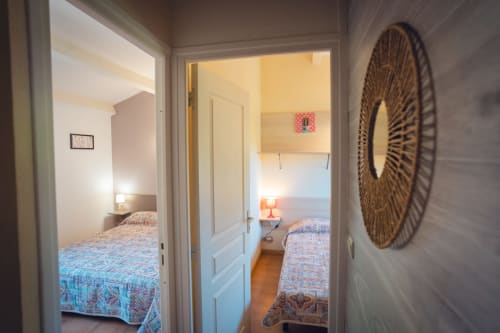 Vue à travers les portes d'une villa à Le Maquis Plage montrant plusieurs chambres avec lits et décoration murale tissée