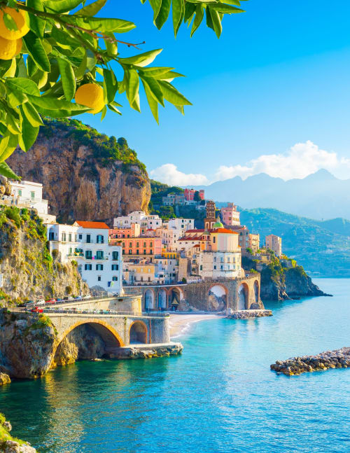 Pittoresco villaggio colorato sulla scogliera con mare turchese, rami di limone in primo piano, vicino Pompei Italia