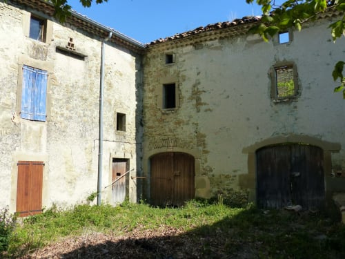Rustic stone courtyard at L'Amiradou BnB in Félines-sur-Rimandoule with aged buildings and wooden doors