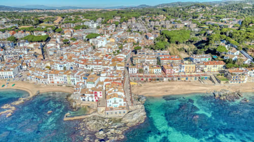Aerial view of Palafrugell coastal town with terracotta rooftops, beach, and turquoise Mediterranean waters