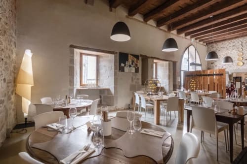 Salle à manger élégante du restaurant Home Horizon SBL à Limoges avec luminaires suspendus modernes, murs en pierre et design contemporain blanc