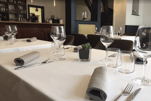Salle à manger élégante à Home Horizon SBL à Limoges avec table blanche dressée formellement, verres à vin et chaises foncées