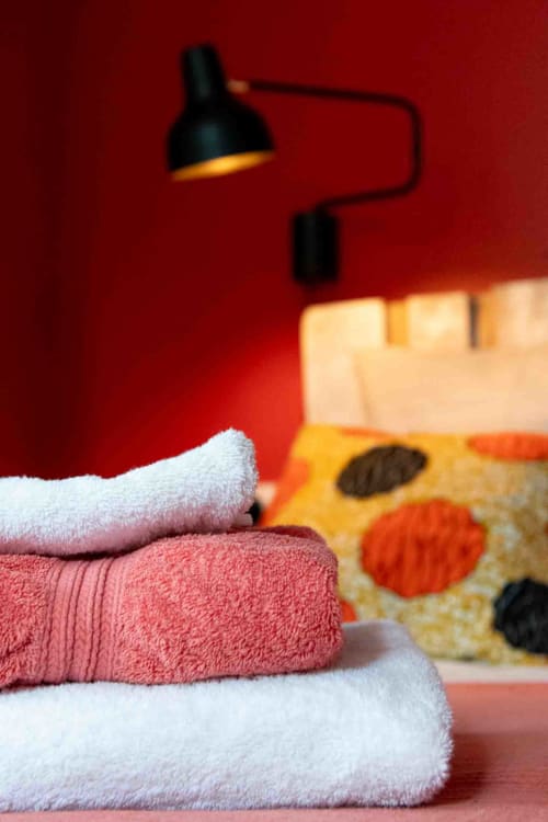 Serviettes douces empilées devant lit coloré, chambre élégante maison d’hôtes à Evry, France, Essonne, atmosphère chaleureuse, confort raffiné.