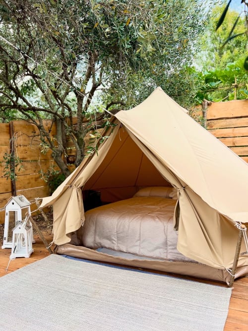 Tente glamping en toile beige avec lit, nichée sous les oliviers du jardin Dolceacqua à l'Agriturismo Stecadò