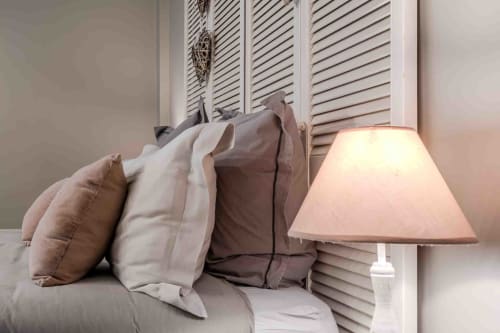 Détail lit cosy avec coussins et lampe douce, chambre maison d’hôtes à Evry, Essonne, France, charme, confort, ambiance apaisante d'une maison de famille