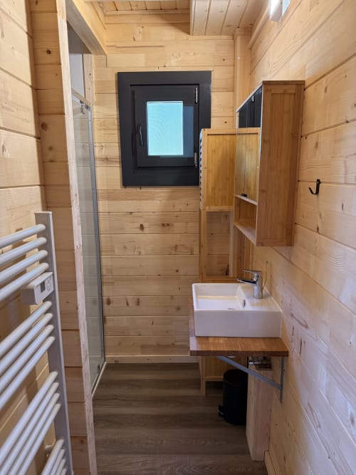 Bagno moderno in lodge in legno presso Cabanes du Belvédère con lavabo, doccia, scaldasalviette e finestra panoramica