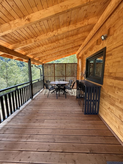 Terrazza in legno con tavolo da pranzo, sedie nere e vista sulle montagne a villa La Colibă