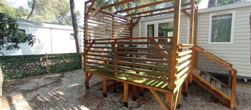 Chalet en bois à parois ajourées et balustrade à Camping La Lézardière, La Valette du Var, entouré d'arbres et terrasse en gravier