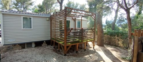 Mobil-home avec terrasse en bois au Camping La Lézardière, entouré d'arbres à La Valette du Var
