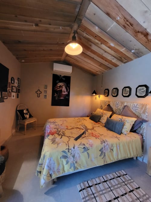 Chambre accueillante au Cabanon du Clos à L'Isle-sur-la-Sorgue avec literie fleurie, poutres en bois et vue sur le jardin