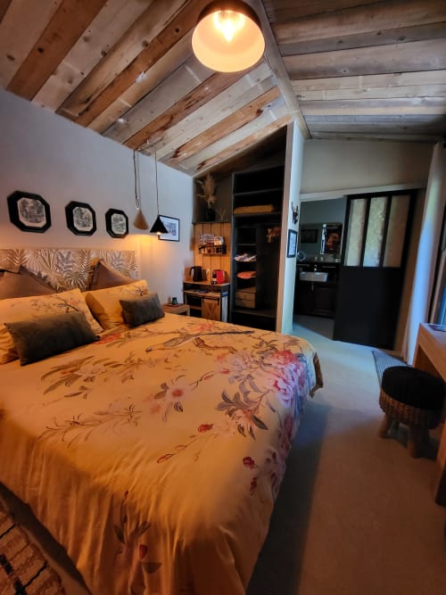 Chambre douillette au Cabanon du Clos avec literie fleurie, poutres en bois et ambiance chaleureuse à L'Isle-sur-la-Sorgue