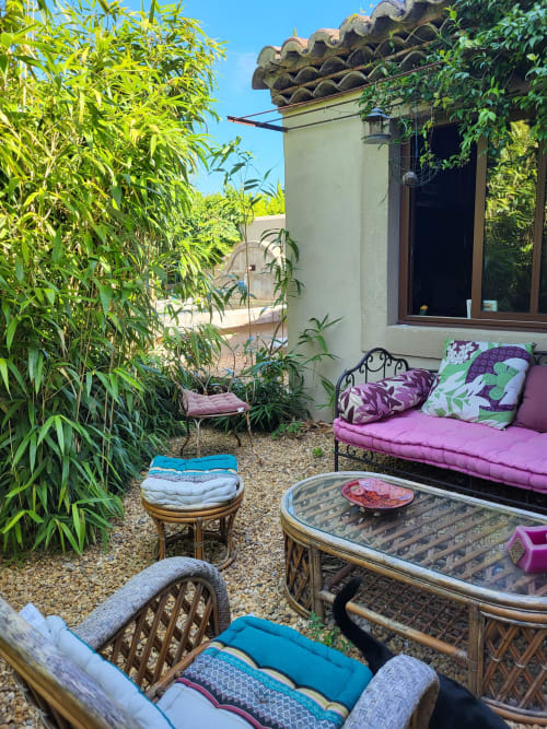 Charmante cour jardinnée au Cabanon du Clos avec bambous, mobilier en rotin et coussins rose