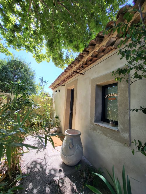 Entrée du salon de jardin Le Cabanon du Clos avec toit en terre cuite, plantes en pot et lierre à L'Isle-sur-la-Sorgue
