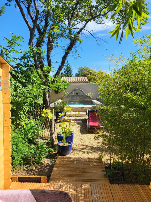 Allée du jardin au gîte Le Cabanon du Clos à Isle sur la Sorgue, avec piscine et transats visibles au-delà des haies paysagères