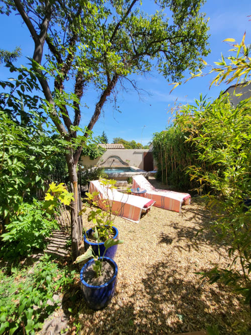 Terrasse ensoleillée au Cabanon du Clos, Île sur la Sorgue, avec transats, plantes en pots et vue sur la piscine