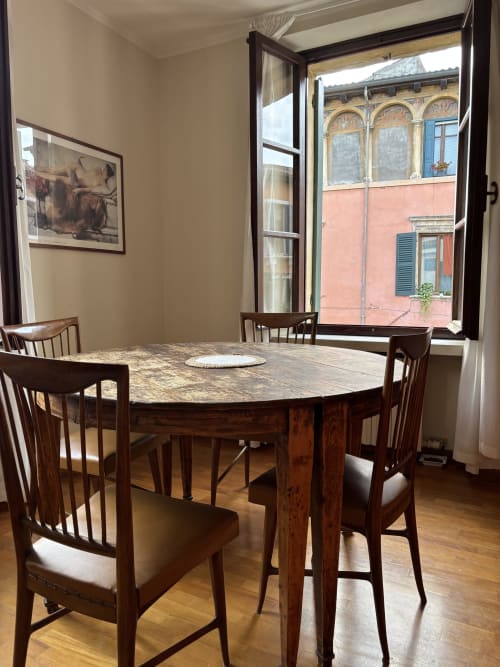 Elegante sala da pranzo a Dimore Verona con tavolo in legno, sedie e vista sulla città di Verona dalle finestre aperte