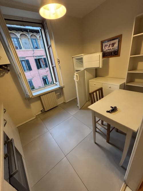Cucina luminosa nell'appartamento Dimore Verona con vista sulla città, mobili bianchi, tavolo da pranzo e finiture moderne