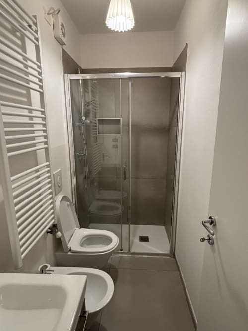 Bagno moderno dell'appartamento Dimore Verona con doccia walk-in, wc, bidet, scaldasalviette e illuminazione contemporanea.