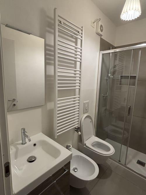 Bagno moderno a Dimore Verona con lavabo bianco, wc, bidet, scaldasalviette e box doccia in vetro
