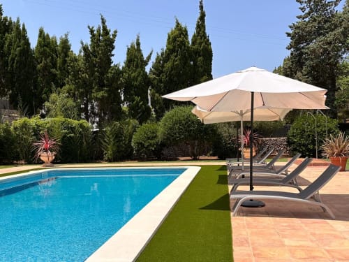 Zona de piscina de lujo Las Golondrinas con tumbonas y sombrilla con vistas a jardines mediterráneos