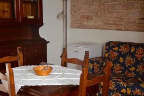 Sala da pranzo rustica presso Residenza San Jacopo a Spello con mobili in legno, divano rivestito floreale e arredi tradizionali