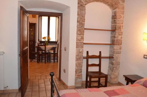Camera da letto dell'appartamento a Spello con pavimenti in cotto, volta in pietra a vista, mobili in legno e vista sulla zona pranzo