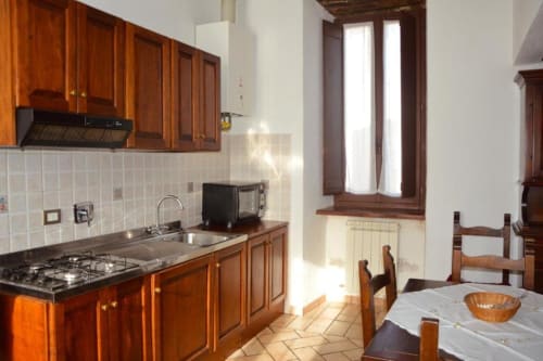 Cucina dell'appartamento a Spello con mobili in legno, piano cottura, zona pranzo e finestre luminose sulla città