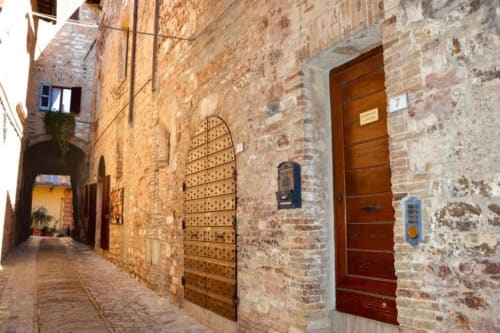 Stretto vicolo in ciottolato a Spello con edifici in laterizio, porte in legno e architettura tradizionale