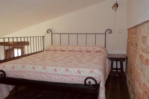 Camera da letto accogliente con letto in ferro battuto e biancheria floreale rosa presso la Residenza San Jacopo, affitto appartamento a Spello