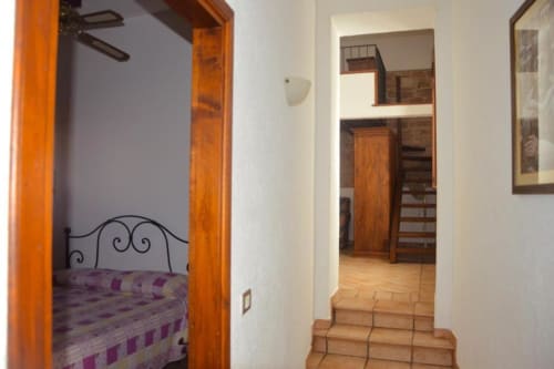 Corridoio della camera da letto con ornata cornice di legno in appartamento a Spello, con testiera in metallo e pavimenti in cotto