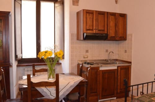 Accogliente zona pranzo in cucina alla Residenza San Jacopo a Spello con mobili in legno, fiori gialli e finestre con vista sulla città