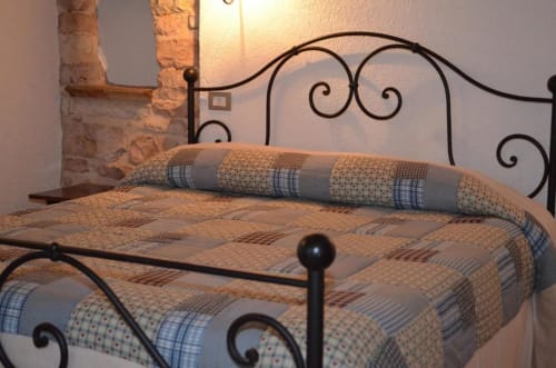 Camera da letto con letto in ferro battuto ornamentale e coperta patchwork presso la Residenza San Jacopo, Spello