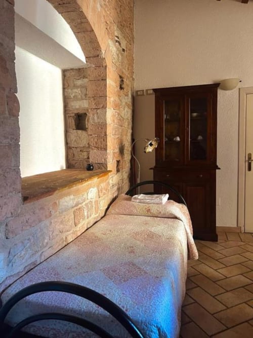 Camera da letto in pietra rustica con pavimenti in cotto e persiane in legno presso la Residenza San Jacopo, Spello