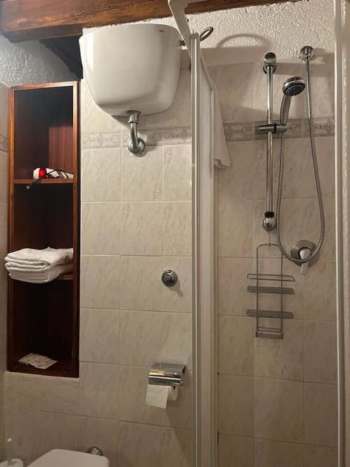 Bagno moderno alla Residenza San Jacopo a Spello con doccia walk-in, rubinetteria a parete e scaffali di stoccaggio