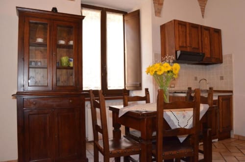 Sala da pranzo rustica con mobili in legno, fiori gialli e angolo cucina nell'appartamento di Spello